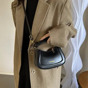 Détail d'un sac hobo noir avec logo Tidal Dryness doré sur un manteau en laine