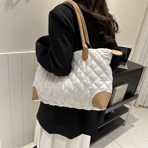 Détail du sac fourre-tout matelassé blanc avec touches de cuir marron porté à l'épaule