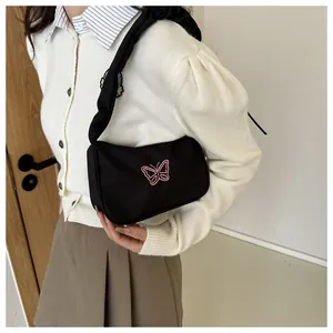 Detalle del bolso de hombro negro plisado con un elegante bordado de mariposa rosa