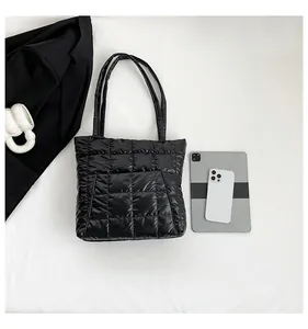 Close-up of black quilted puffer tote bag with laptop and modern accessories