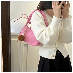 Dettaglio borsa a spalla rosa con ricamo a farfalla e tracolla con design a pieghe