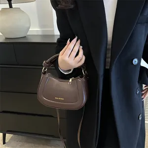 Détail du sac à main marron foncé avec poignée nouée et logo doré tidal dryness