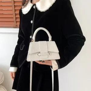 Détail du sac à main blanc crème avec texture tissée, poignée rigide et bandoulière