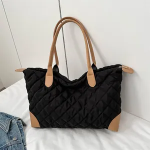 Détail du grand sac cabas matelassé noir avec anses en cuir marron et fermeture éclair