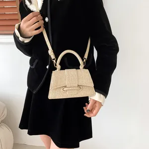 Texture tissée détaillée d'un sac bandoulière trapèze beige avec ferrures dorées