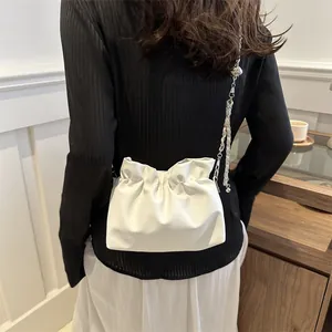 Détail du sac seau nuage plissé blanc avec texture en cuir et fine bandoulière chaîne