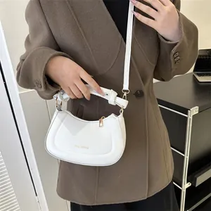 Détails du sac demi-lune blanc avec poignée nouée et finitions métalliques dorées