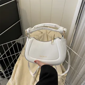 Gros plan d'un sac demi-lune blanc avec zip doré et texte Tidal Dryness gravé