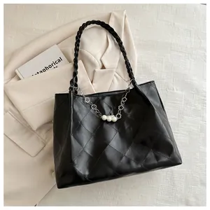 Detail of black quilted tote bag with pearl flower chain and woven leather handles
