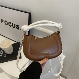 Gros plan du sac en cuir marron avec anse nouée blanche duveteuse et fermeture éclair dorée