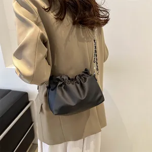 Gros plan du sac seau noir plissé avec bandoulière en chaîne argentée et texture mate douce