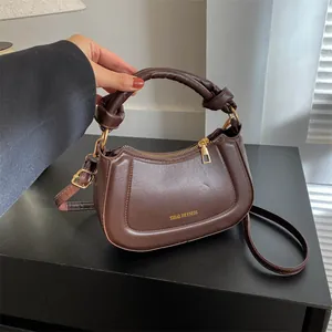Détail d'un sac à main vintage marron avec poignée nouée et logo doré brillant