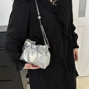 Sac seau argenté métallisé avec bandoulière chaîne porté par un mannequin femme