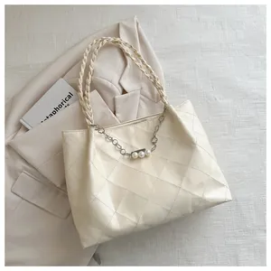 Detailed close-up of cream quilted tote bag with pearl chain and braided strap