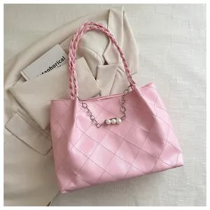 Close-up of pink quilted tote bag featuring woven handles and pearl flower chain