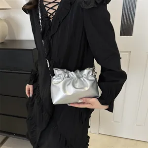 Détail d'un sac seau plissé argenté métallisé avec bandoulière chaîne porté par un modèle