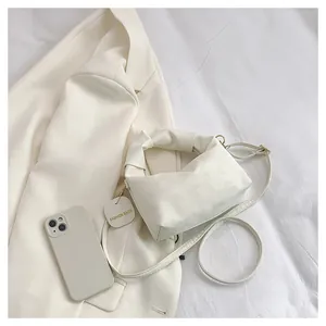 Overhead view of creamy white handbag with pleated handle and thin shoulder strap