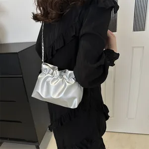 Détail du sac seau argenté plissé avec bandoulière chaîne porté par un modèle