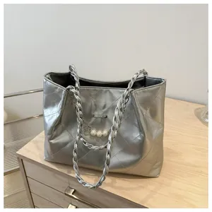 Detail of silver quilted tote bag featuring pearl chain and metallic woven shoulder strap