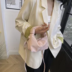 Detail of light pink satin dumpling bag with knot handle and gold zipper accessory