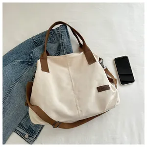 Detail of canvas tote bag with adjustable brown shoulder strap and fashion leather tag