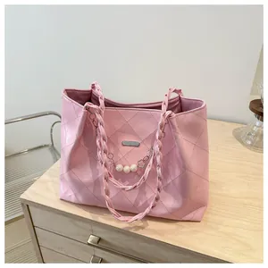 Close-up of pink quilted tote bag with braided handle and decorative pearl chain detail