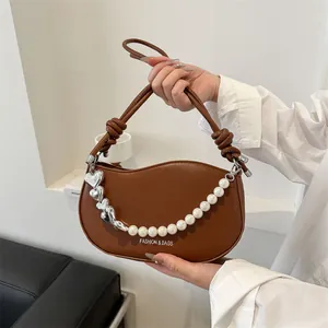 Detailed close-up of the stylish brown shoulder bag featuring pearl and heart chain decor.