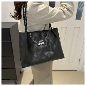 Detail of black quilted tote bag with pearl chain and woven shoulder strap