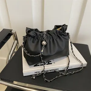 Détail du sac seau noir plissé avec chaîne argentée et sphère métallique décorative