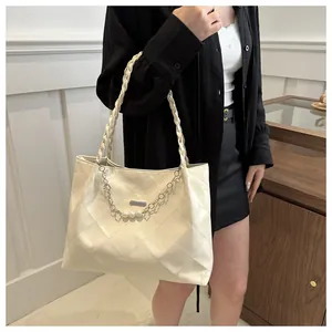 Detail of cream tote bag featuring quilted pattern and pearl floral decorative chain