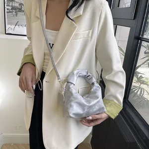 Detail of silver pleated cloud bag with metallic finish and detachable strap
