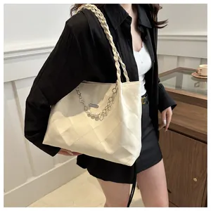 Close-up of quilted cream tote bag with pearl chain details in a cozy cafe setting