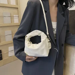 White ruched cloud-style crossbody bag with gold fashion tag and adjustable shoulder strap