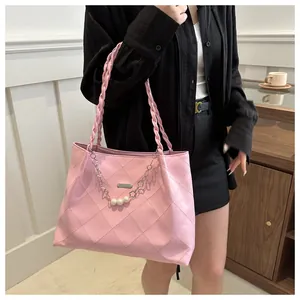 Detail of pink quilted tote bag featuring braided rope straps and pearl chain charm