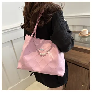 Pink quilted tote bag detail with pearl chain decor and woven strap on model shoulder