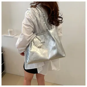 Close-up of a silver quilted tote bag with pearl pendant and metallic finish details