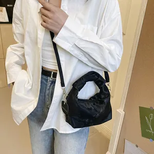 Elegant black pleated handbag with knotted handle and glossy satin finish cross-body style