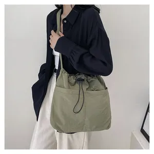 Detail of olive green drawstring crossbody bag showing fabric texture and side pocket