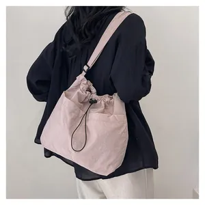 Back view of pink drawstring crossbody bag with wide shoulder strap on model