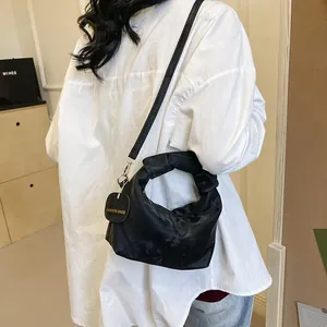 Detail of black pleated fabric handbag with knotted handle and slim shoulder strap