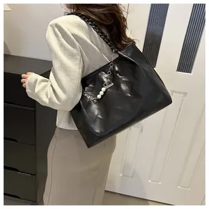 Detail view of black quilted tote bag with large capacity and pearl clover charm accessory