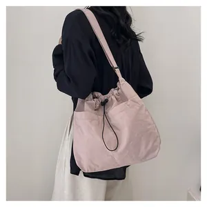 Pink nylon crossbody bag with drawstring detail and adjustable strap shown on model