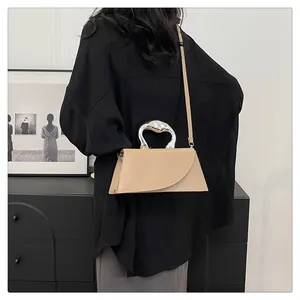 Detailansicht der cremefarbenen Ledertasche mit markantem silbernen Bogen-Metallgriff