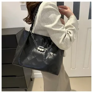 Model wearing a black quilted tote bag with pearl chain detail for a daily commute style