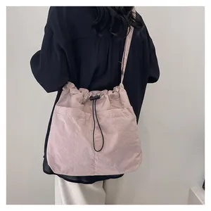 Detail of pink drawstring shoulder bag with visible crinkled texture and outer pockets