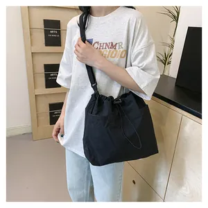 Detail of black canvas crossbody bag featuring functional drawstring pockets and wide strap