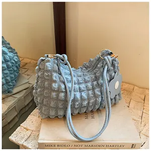 Close-up of light blue pleated fabric handbag with dual rope straps and floral charm