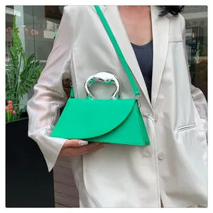 Detail einer grünen Lederhandtasche mit silbernem Metallgriff und Schultergurt