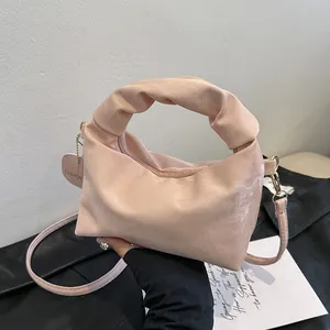 Detail of a pink satin handbag featuring a ruched cloud handle and fashion heart charm