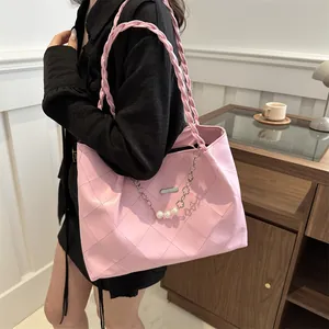 Pink quilted tote bag with woven handle and pearl chain charm on female model